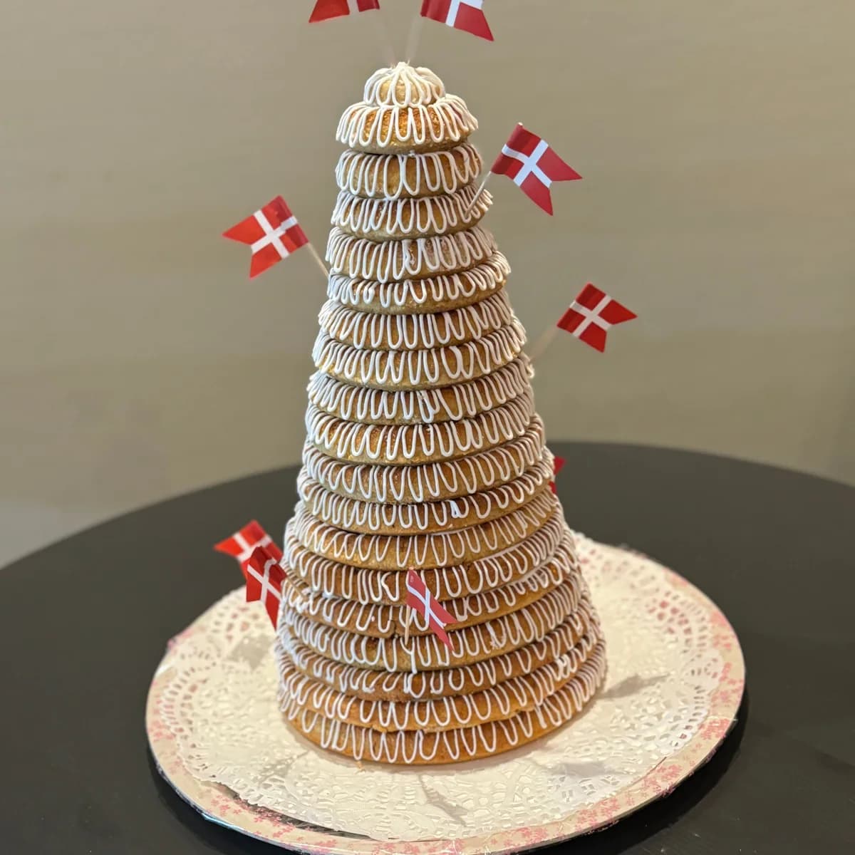 Ett torn av kransekageringar med kristyr och danska flaggor i, på silverfat