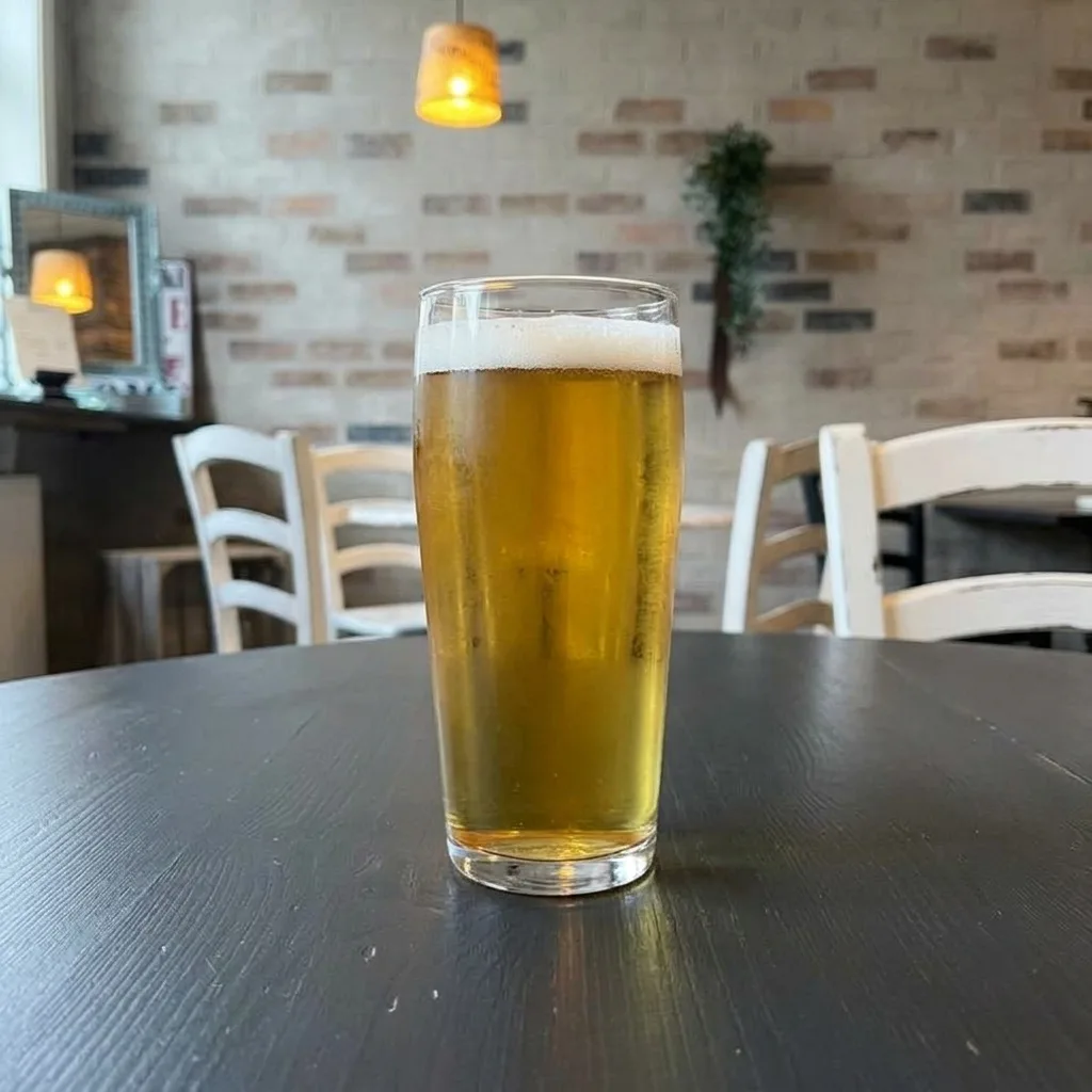 Ett glas dansk pilsner på det mörka bordet, med restaurangen i bakgrunden