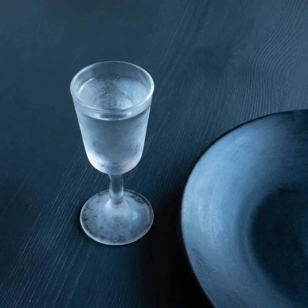 Ett frostat snapsglas intill kanten av en svart tallrik