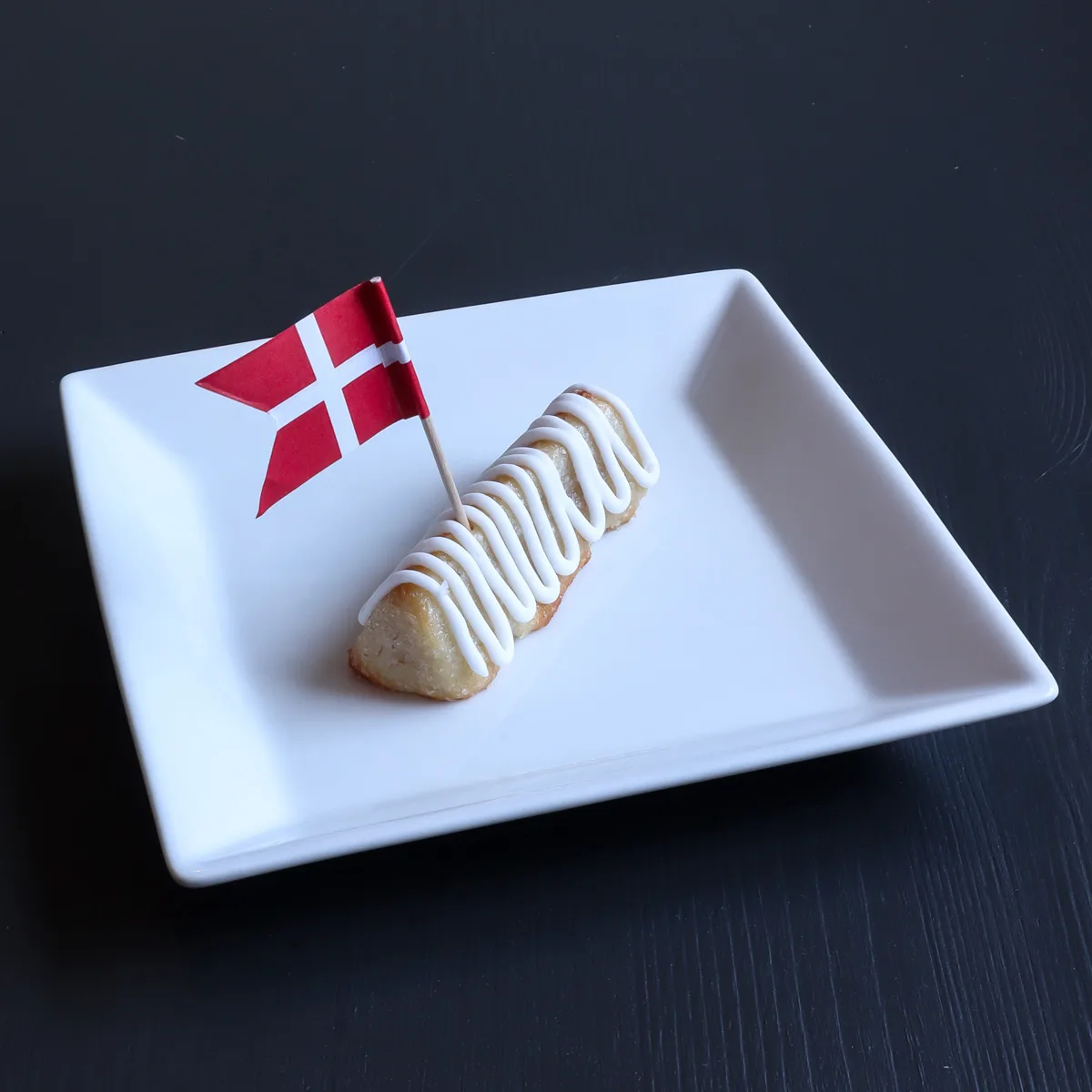 En bit kransekage med kristyr, på vit tallrik med dansk flagga