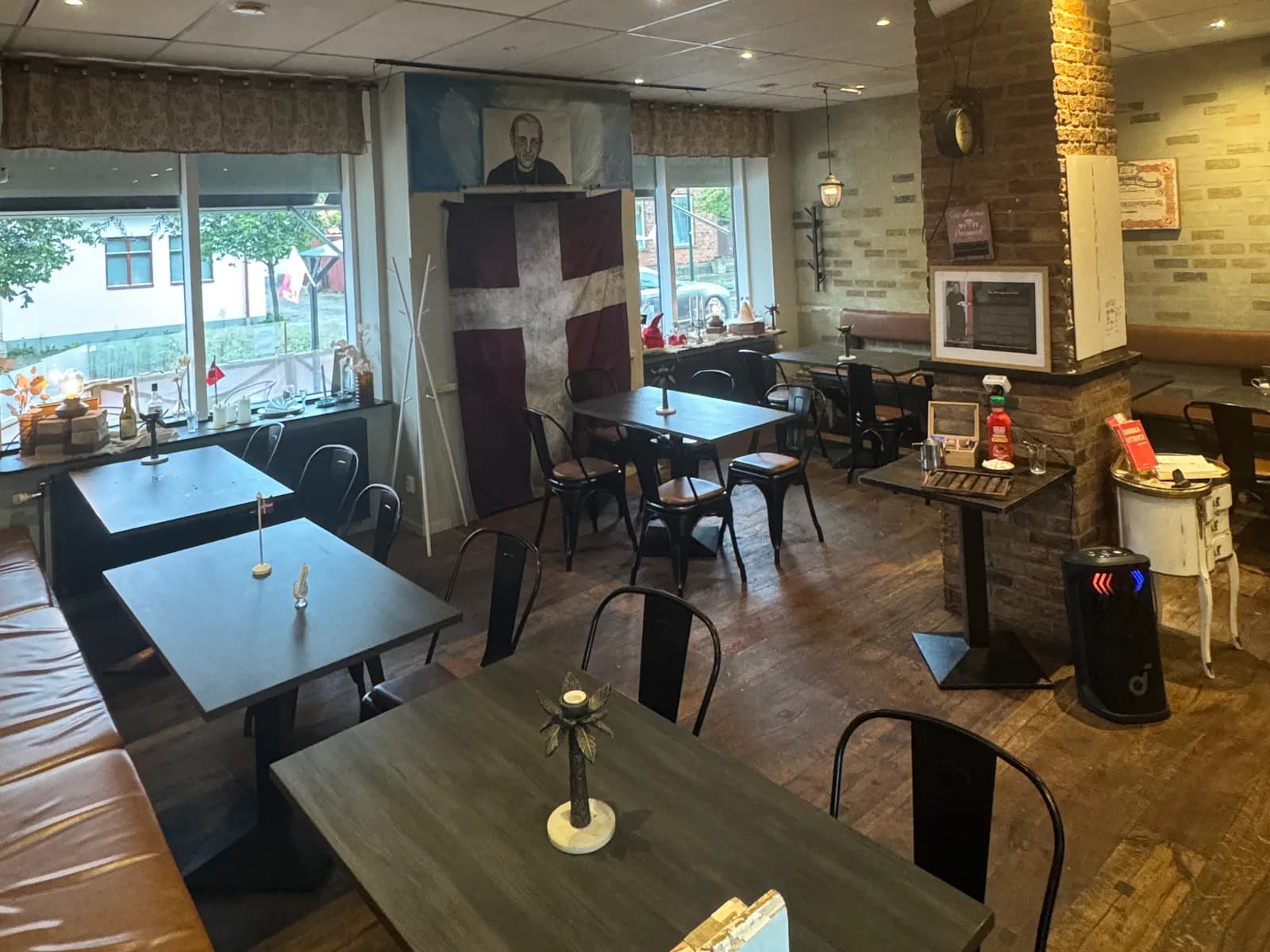 Restaurangens matsal på Norregatan 3, med mörka träbord, Dannebrogen på väggen och fönster mot gatan