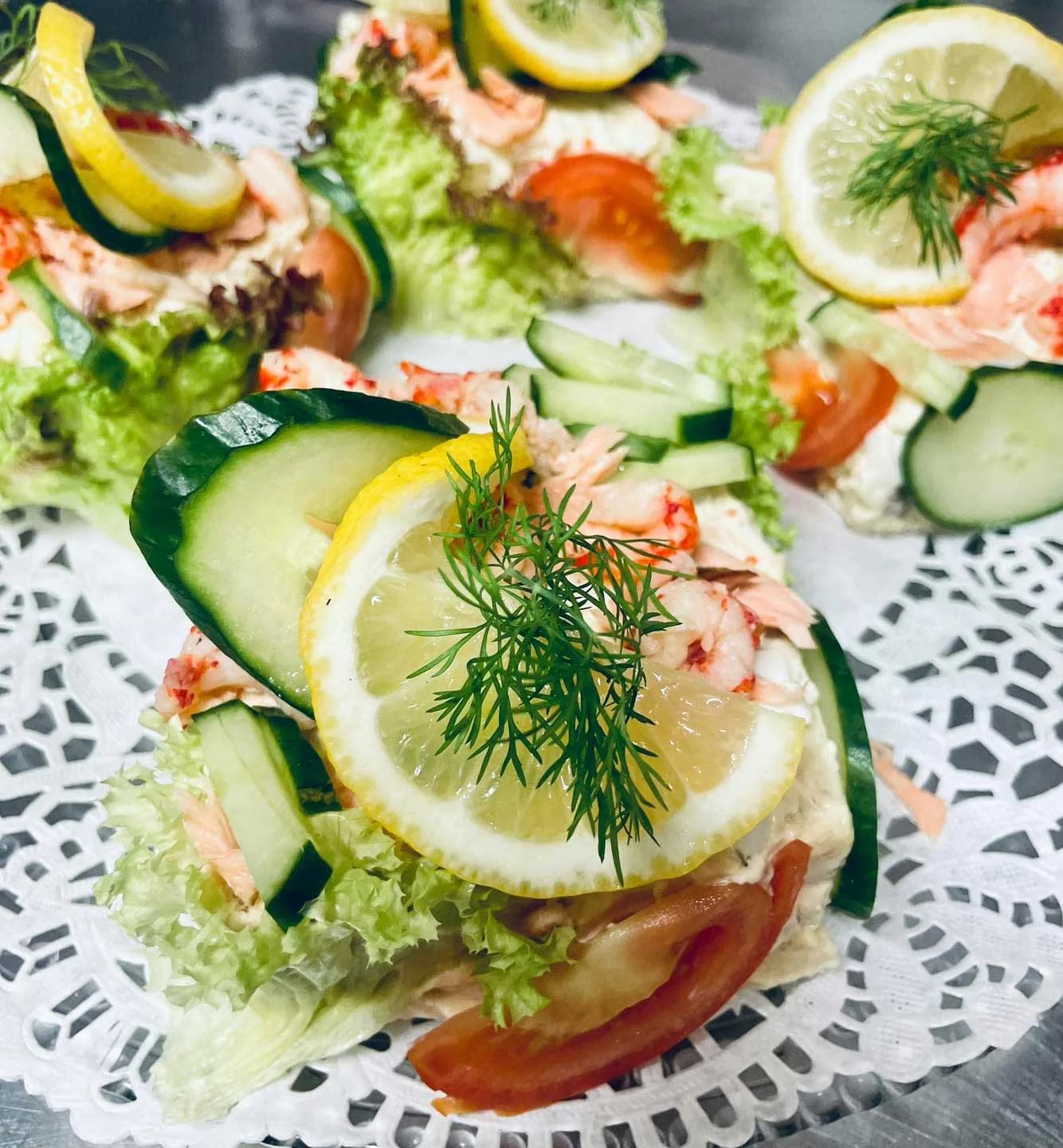 Uppdukade smørrebrød med räkor, kräftstjärtar, citron och dill på tårtpapper