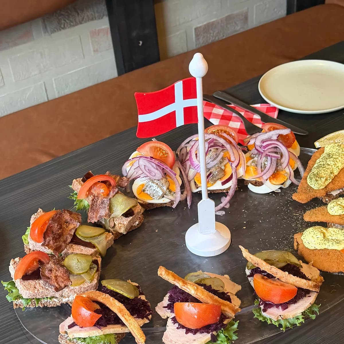 Danskt smørrebrød med räkor, flæskesteg, rostbiff, salami och ost på en svart tallrik